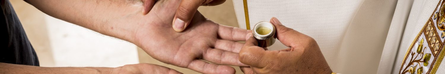 Hands of a Catholic Priest applying the oil for the Anointing of the Sick. Sacraments of the Catholic Christian religion in church.